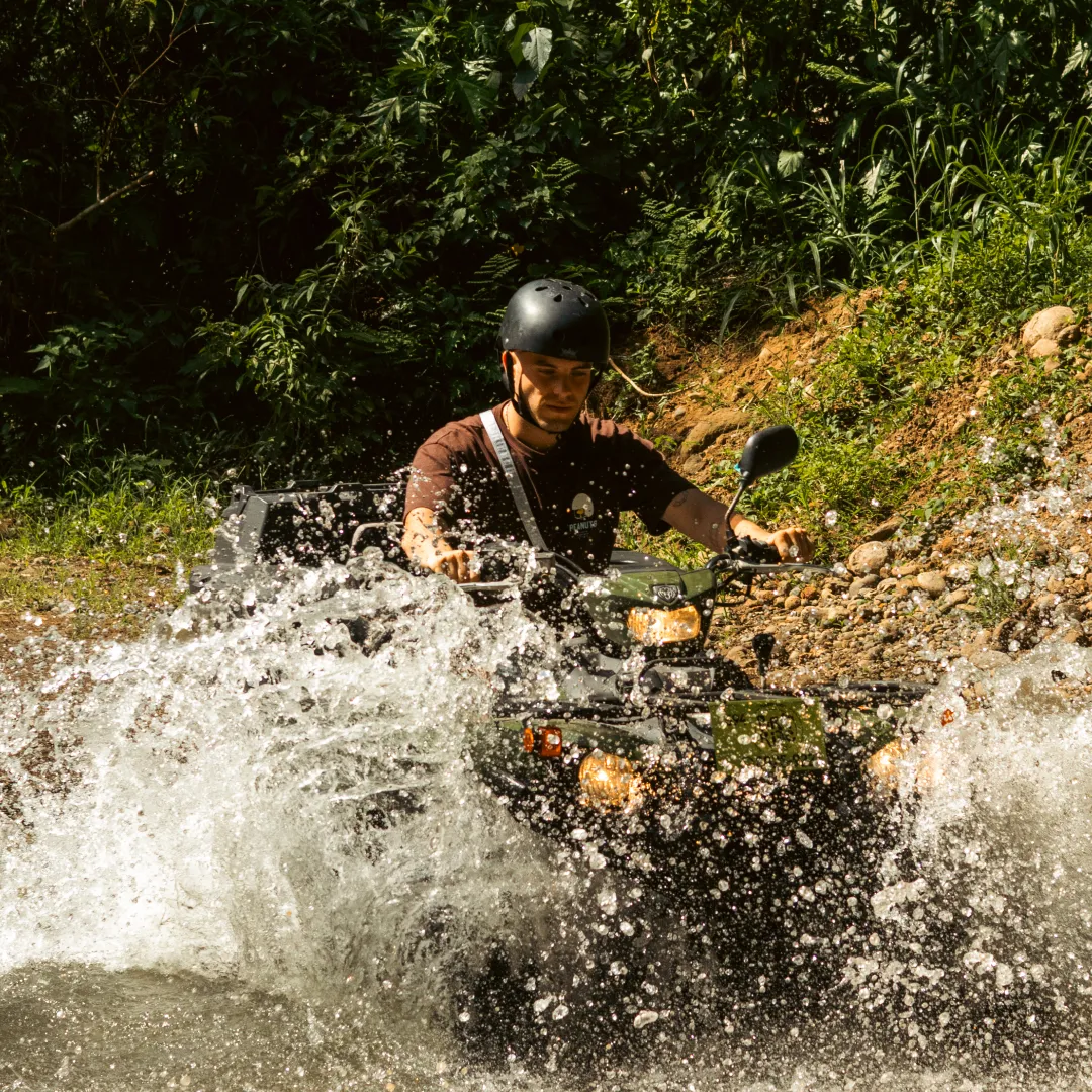 Man riding ATV through water splash
